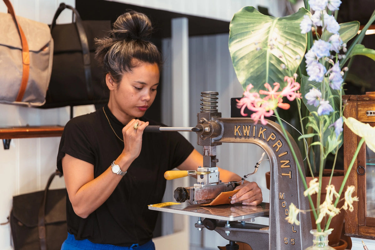 Embossing a name into a leather ID tag on the hand press in our Amsterdam shop