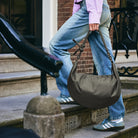 Lea Sling Bag Dark Forest carried by the strap