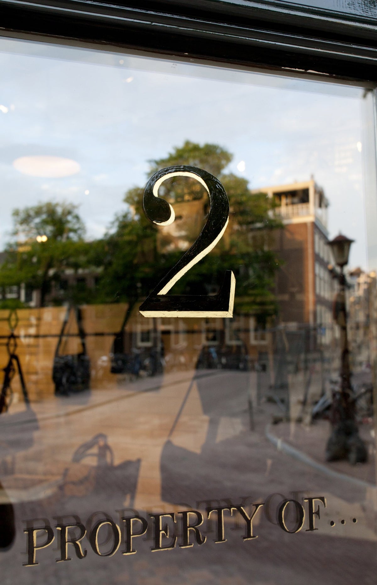 The glass door of our first shop at Herenstraat 2, Amsterdam, with the gold number 2 and Property Of... lettering, 2011