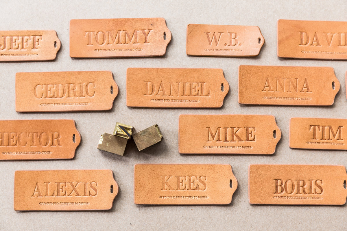 Leather ID tags embossed with first names, next to the brass letters used to stamp them